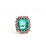 An emerald and diamond entourage ring, featuring a hexagonal step-cut emerald of 13.0 x 11.5 mm,