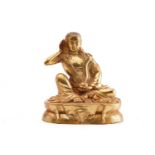 A Chinese gilt bronze figure of Milarepa, seated with his right hand cupped to his ear, a bowl in