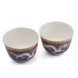 A pair of Chinese porcelain dragon cups, painted with opposing white dragons facing a pearl