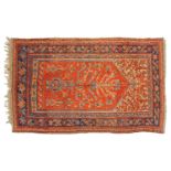 An old Turkish Ushak rug with a stylized tree of life design on a tomato red ground within