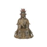 A Chinese bronze figure of Guanyin, seated wearing long robes and holding a mirror, traces of red