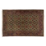 An old Kirman/ Kerman rug with allover floral tiled pattern on a pistachio green ground, within an