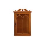 An early 20th-century sycamore single door wall mounted display cabinet with moulded cornice above