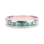 An emerald half eternity ring, with seven square-shaped step-cut emeralds in channel setting, to a