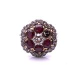 A ruby and diamond cluster ring; the principal round brilliant cut diamond in a raised claw mount