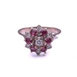 A ruby and diamond cluster ring, comprising a central round brilliant cut diamond above a border