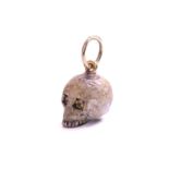 An enamel skull charm pendant, textured and mottled enamel on a sculpted hollow skull, eyes set with