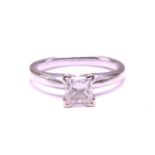 A single-stone diamond ring. The princess cut diamond in raised four claw mount. The diamond is