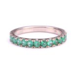 An emerald half eternity ring, consisting of fourteen circular-cut emeralds in U-cut pavé