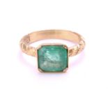 An emerald solitaire ring in 18ct gold, comprising an emerald-cut emerald in light green colour,