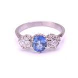 A sapphire and diamond three-stone ring, consisting of an oval-cut sapphire with medium blue colour,