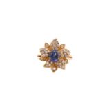 An 18ct gold sapphire and diamond flower ring, comprises an oval sapphire cabochon with a high dome,