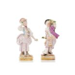 A pair of Meissen figures dressed in purple, the man holding a garland of flowers, both with