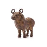 A Chinese patinated and gilt bronze figure of an Oxen with curled horns and a body engraved with