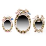 A Dresden style floral encrusted wall mirror, the oval plate surmounted by cherubs with a garland of