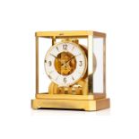 A Jaeger LeCoultre brushed brass Atmos clock, no. 453672, with Arabic numerals at the quarter