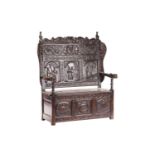 A 19th-century "Jacobethan" box settle with high back and shaped wings the back carved with scenes