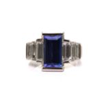 An Art Deco-style platinum tanzanite and diamond ring, featuring a tapered rectangular step-cut