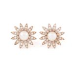 A pair of pearl and diamond daisy head earrings; each stud comprising a round button-shaped pearl