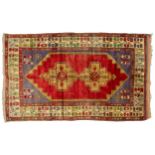 An old red-ground Turkish Konya(?) rug with two cruciform medallions within a broad flowering