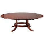 A craftsman-made mahogany segmentally extending circular dining table, 20th century, on a four-
