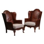 A pair of early 20th-century wingback fireside chairs with arched backs upholstered in original