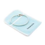 Tiffany & Co. - A two-tone hook and eye bangle, comprising an oval-shaped flat bangle bracelet,