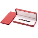 A Cartier ballpoint pen, featuring black resin and gold plated parts with a twist design and set