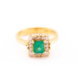 An emerald and diamond entourage ring, centred with an emerald-cut emerald in bright green colour,