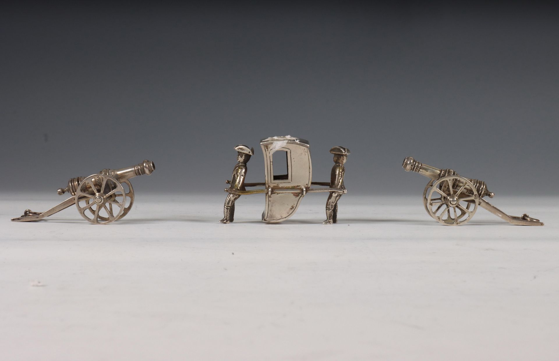 Drie miniaturen: draagstoel met twee dragers, en twee miniaturen, kanon op affuit, vroeg 20e eeuw,