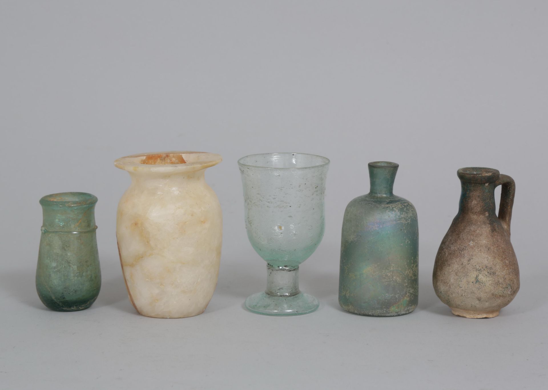 Three glass objects, a faience jar and an albaster pot.