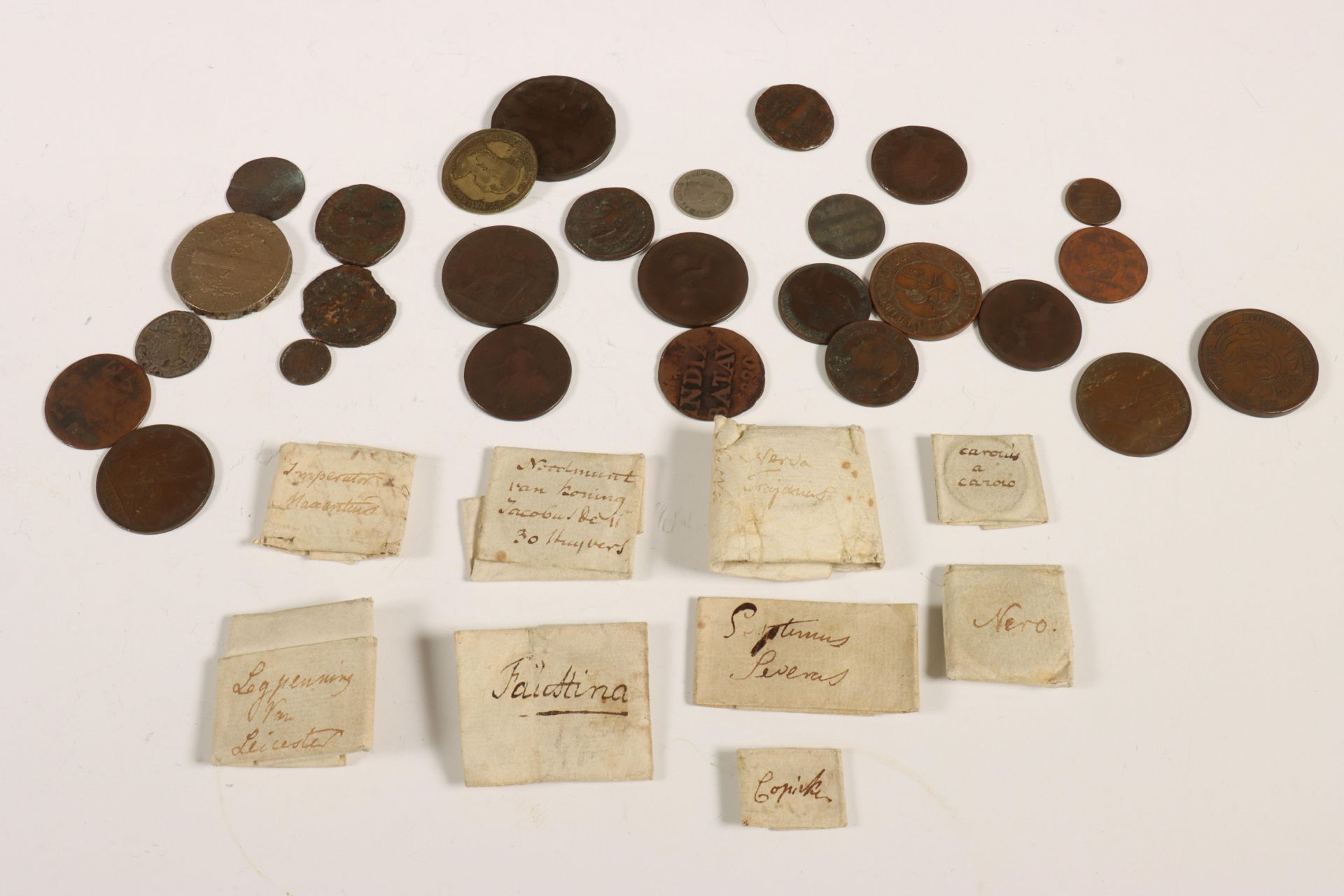 A 19th century collection of eleven Roman bronze copper alloy coins, wrapped in paper with comments 