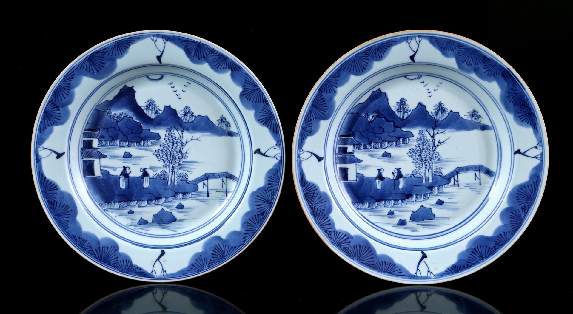 2 dishes with blue and white decor of 2 people in a mountain landscape