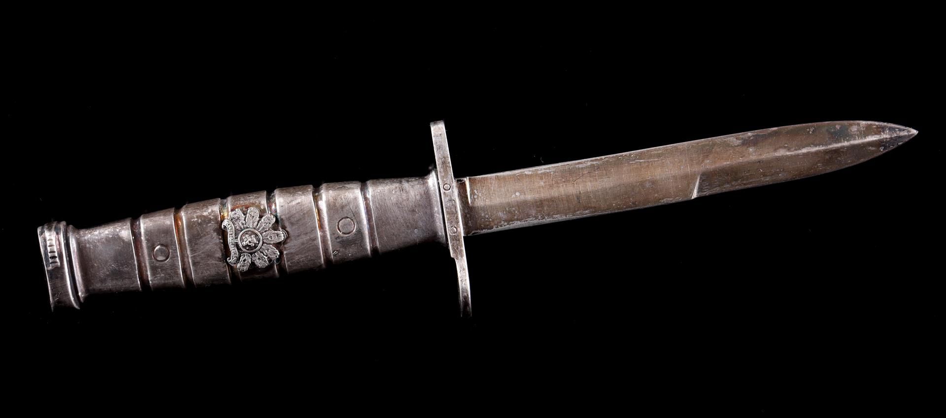 Metal letter opener in the shape of a dagger with an emblem