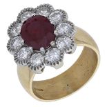 An 18ct gold ruby and diamond cluster ring, the oval mixed-cut ruby within a surround of brillia...