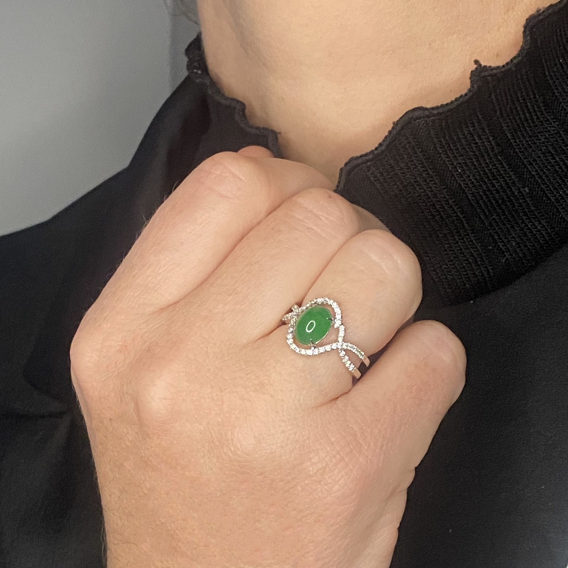 A jade and diamond ring, the jade cabochon claw-set within an entwined surround of brilliant... - Image 3 of 3