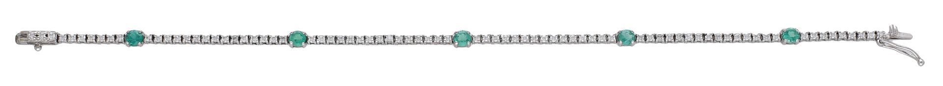 A diamond and emerald line bracelet, composed of a series of brilliant-cut diamonds spaced b...