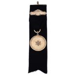An early 20th century gold and diamond set presentation medallion on fob, the black grosgrai...