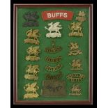 The Buffs Cap Badges and Shoulder Titles. A framed display of 11 Buffs cap badges; 5 should...