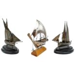 THREE MINIATURE SILVERED-METAL MODEL SAILING BOATS 20TH CENTURY raised on wooden bases.  14cm long