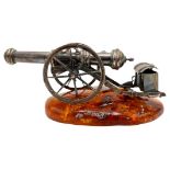 SILVERED-METAL MINIATURE CANNON ON AN AMBER BASE 20TH CENTURY 10cm long approx. PROVENANCE : Private