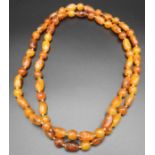 AN AMBER BEAD NECKLACE, with naturalistic form beads, 58 cm long