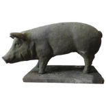 A RECONSTITUTED STONE FIGURE OF PIG ON A PLINTH BASE, 55cm x 95cm