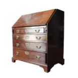 A GEORGE III MAHOGANY BUREAU, the fall front over a fitted interior with three long drawers and upon