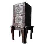 A CARVED OAK CUPBOARD ON STAND, the cupboard fitted with interior compartments and drawers, the