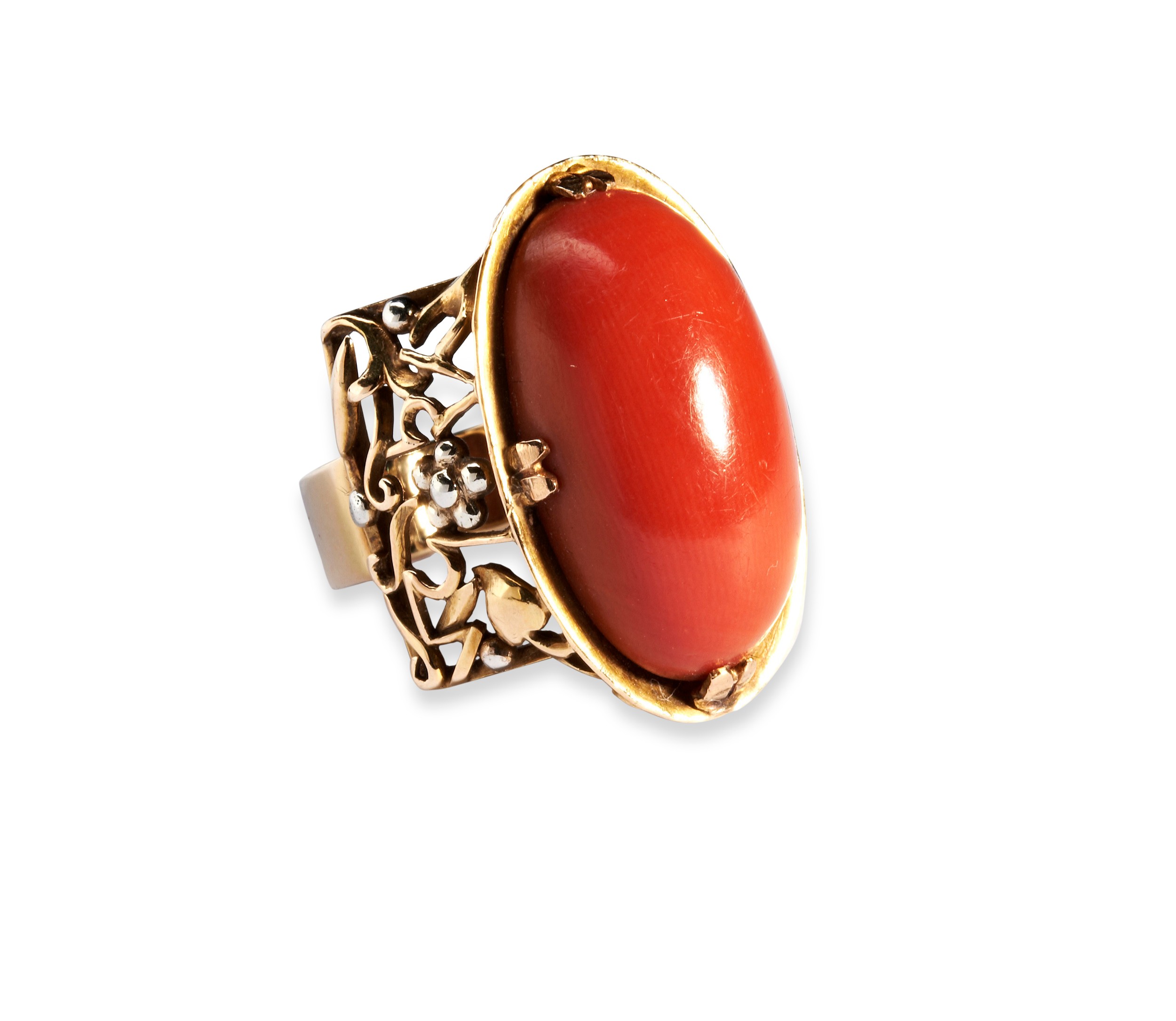 AN ARTS AND CRAFTS CORAL AND GOLD RING the oval cabochon-cut coral, four double claw set on an