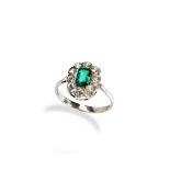 AN EMERALD AND DIAMOND CLUSTER RING, CIRCA 1900 the step-cut emerald, collet set within a border