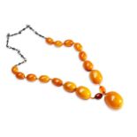 AN AMBER BEAD NECKLACE a single row of graduated amber beads made up of fifteen oval opaque orange