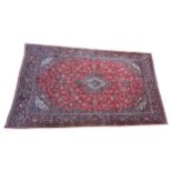 A LARGE HANDKOTTED PERSIAN KASHAN CARPET, red, biege and pale blue floral motifs on a dark blue