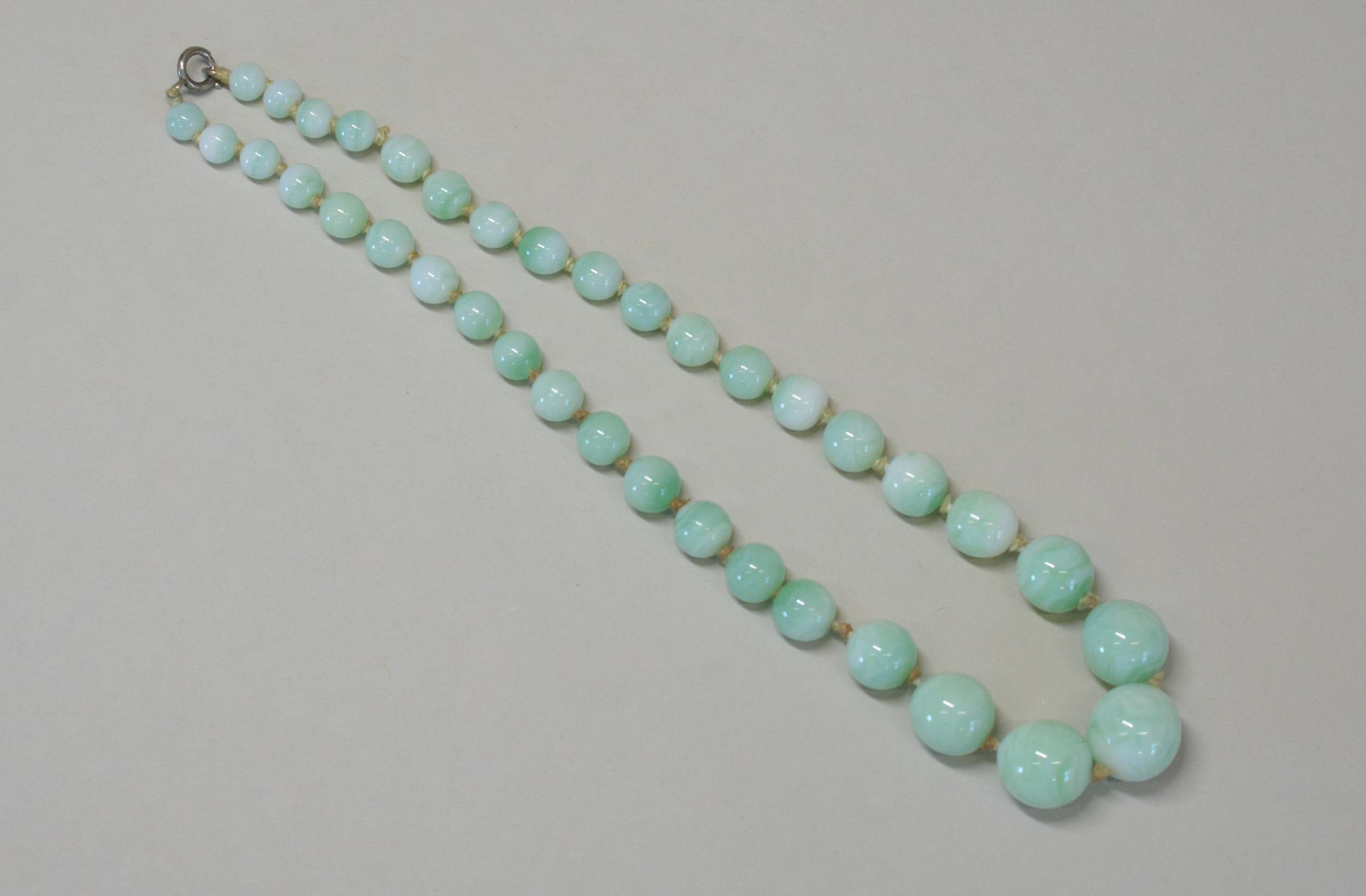 A GLASS IMITATION JADE BEAD NECKLACE Graduating green glass beads with silver bolt fastening. Weight